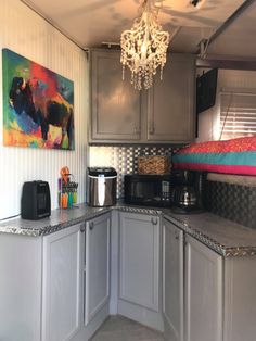 a kitchen with gray cabinets and a chandelier hanging from the ceiling above it