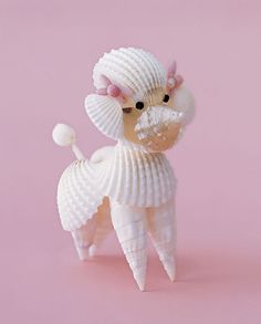 a small toy dog made out of seashells on a pink background