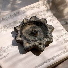 an old cast iron candle holder sitting on top of a white tablecloth covered table