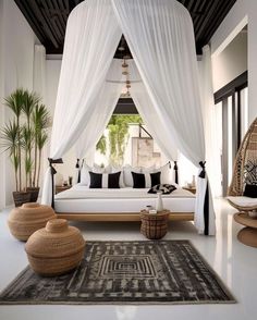 a white bed sitting in the middle of a living room next to a large window