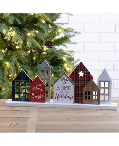 a wooden house with christmas decorations on the front and side, sitting in front of a christmas tree