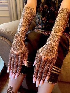 a woman sitting on top of a couch with her hands covered in henna tattoos