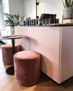 two pink stools sitting in front of a counter