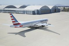 an american airlines plane parked on the tarmac in front of hangars at an airport