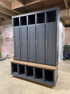 a large gray cabinet sitting in the middle of a room next to a wooden bench