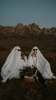 two women dressed in white sitting on the ground with their heads covered by veils