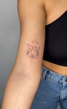 a woman's arm with a tattoo on it and a small tiger head in the middle