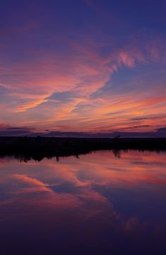 the sky is reflecting in the water at sunset