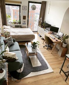 a living room filled with furniture and a large window next to a wooden floor covered in plants