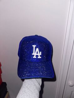 a person's hand holding up a baseball cap with the los angeles dodgers on it