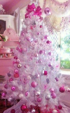 a white christmas tree decorated with pink and silver ornaments