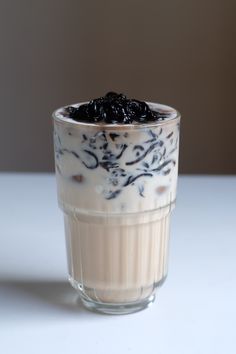 a glass filled with milk and raisins sitting on top of a white table