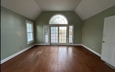 an empty room with hard wood floors and arched window