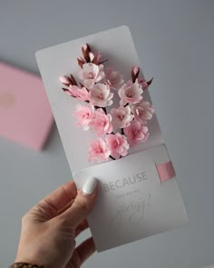 a person holding a card with pink flowers on it