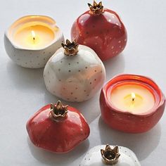 four ceramic apples and two candles on a white surface