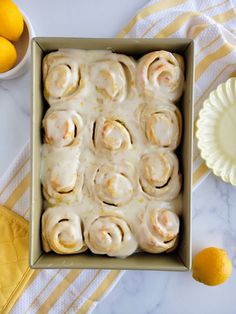 lemon sweet rolls with icing in a baking pan on a yellow and white tablecloth