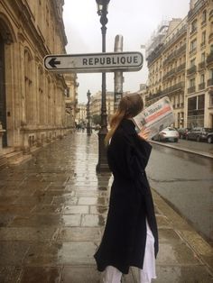 a woman is standing on the street reading a newspaper