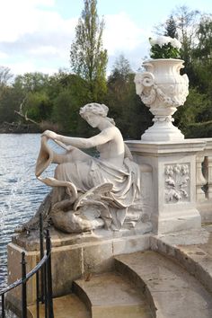 a statue sitting on top of a stone wall next to a body of water