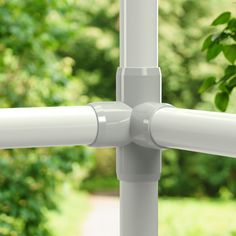 a close up of a white metal pole with trees in the back ground behind it