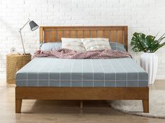 a bed with a wooden headboard and foot board next to a potted plant