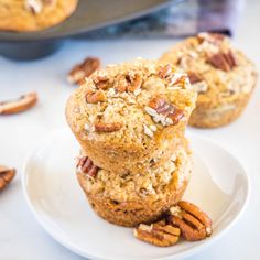 three muffins stacked on top of each other with pecans in the background