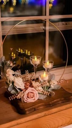 a table topped with candles and flowers on top of a wooden counter next to a window