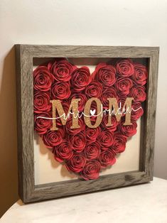 a heart made out of red roses with the word mom spelled in gold on it