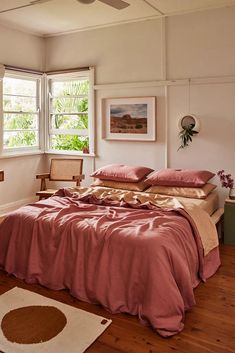 a bed sitting in a bedroom under a window next to a rug and wooden floor