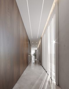 an empty hallway with light coming through the windows and wood paneling on the walls