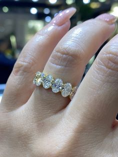 a woman's hand with a five stone ring on top of her finger, in front of a store window