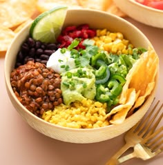 a bowl filled with beans, rice and guacamole next to tortilla chips