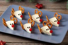 some food is on a blue plate and decorated with pretzels as reindeer noses