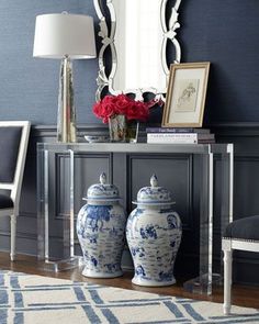 two blue and white vases sitting on top of a table next to a mirror