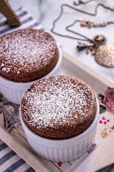 two cakes sitting on top of a tray covered in powdered sugar