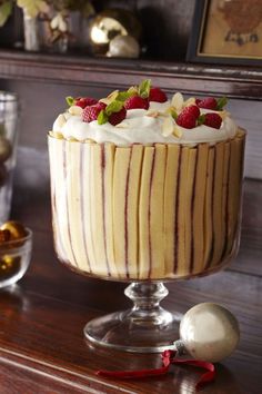 a cake with white frosting and raspberries on top sitting on a table