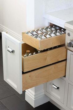 an open drawer in a kitchen with white cabinets and drawers on the bottom, filled with cans