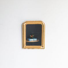 there is a small gold frame on the wall with a flower arrangement in front of it