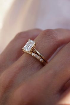 a woman's hand with a gold ring and diamond engagement ring on her finger