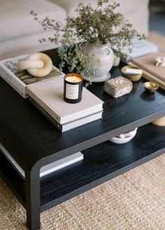 a coffee table topped with books and a candle