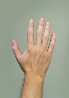 a person's hand with pink nail polish holding their fingers up in the air