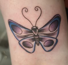 a small tattoo of a butterfly on the leg, with blue and purple colors in it's wings