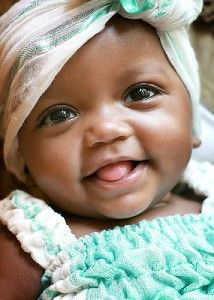 a smiling baby wearing a green and white headband on top of it's head