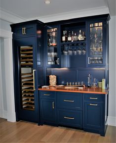 a kitchen with blue cabinets and wooden counter tops, wine glasses on the cabinet doors