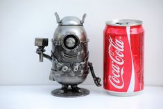 a metal robot next to a can of coke