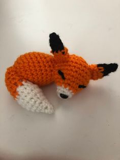 an orange knitted toy laying on top of a white table