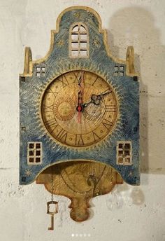 an old clock is hanging on the side of a white wall with a key attached to it