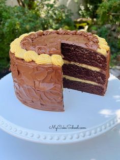 a chocolate cake with yellow frosting is on a white plate and has one slice cut out