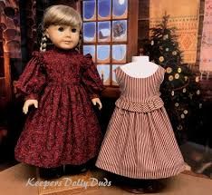 two dolls are standing next to each other in front of a christmas tree and window