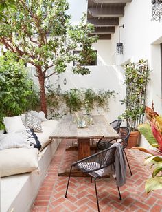 an outdoor dining area with couches, tables and potted plants