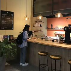 a woman standing in front of a counter at a coffee shop